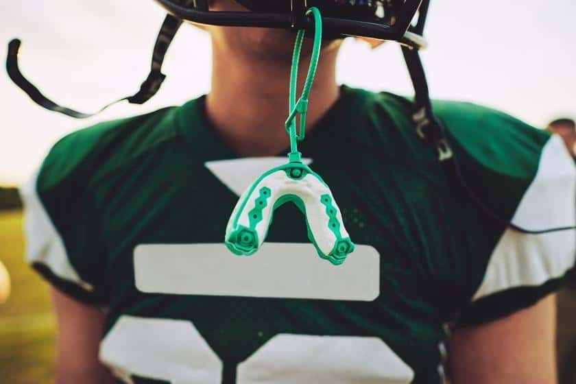 Mouthguard hanging from a football helmet from a strap.