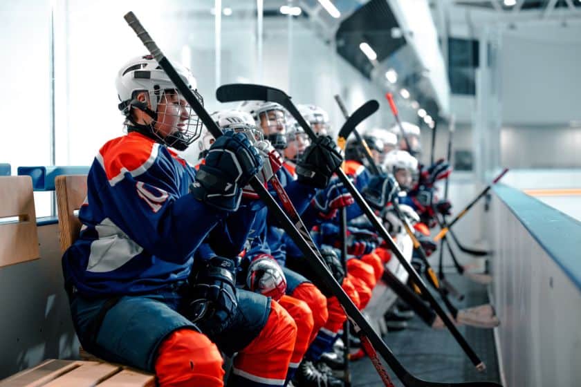 Hockey players sitting on the players box.