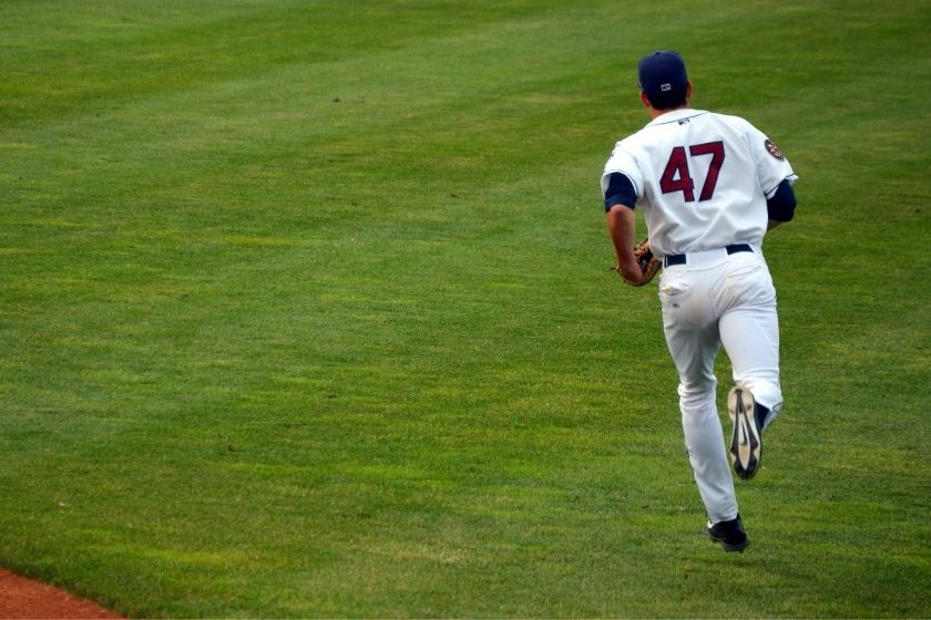 Baseball player with a jersey number 47 running bases on grass